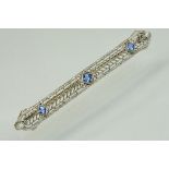 Sapphire 18ct white gold bar brooch, three square mixed cut blue sapphires, the principal sapphire