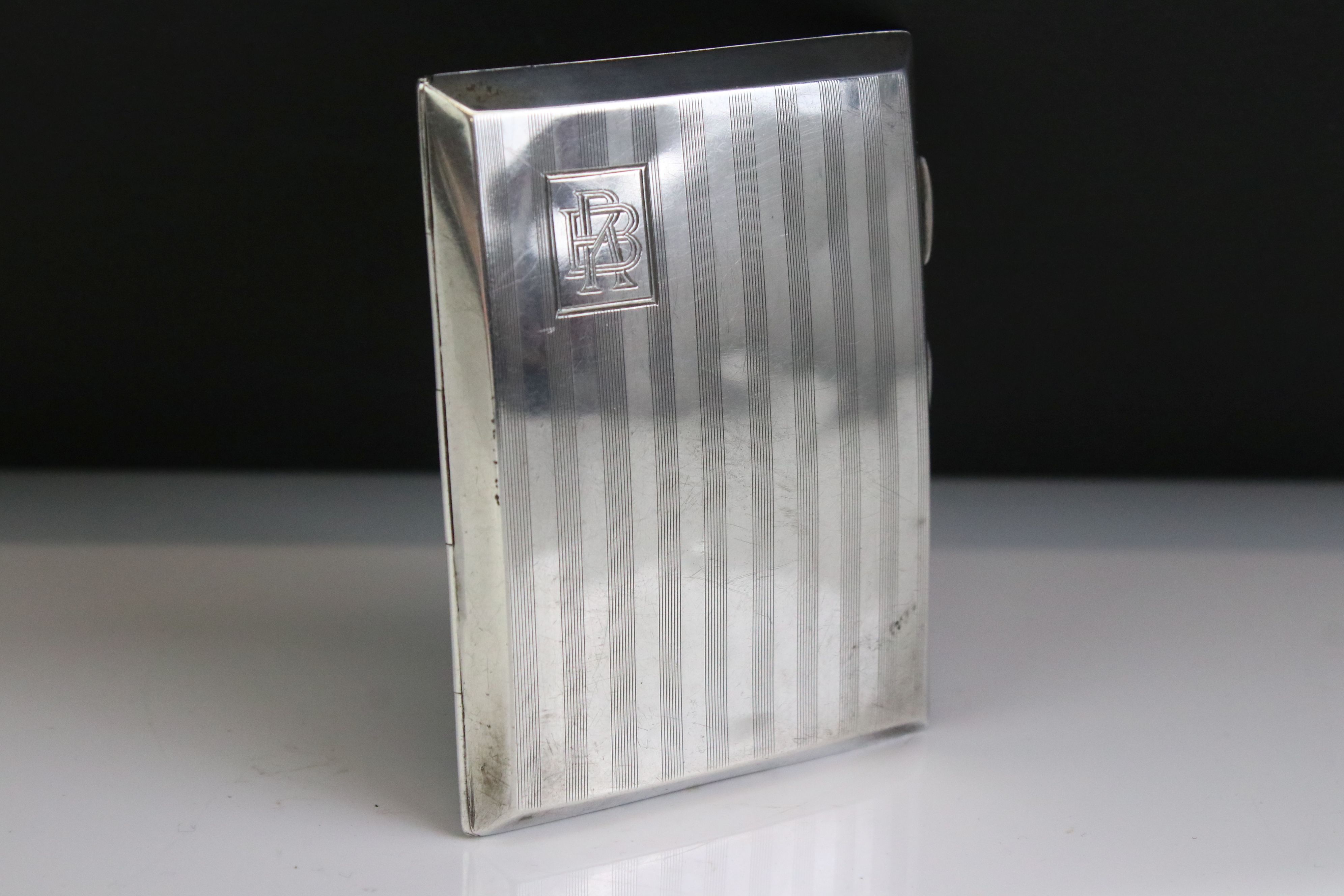 George V silver cigarette case of curved rectangular form, with engine turned striped decoration,