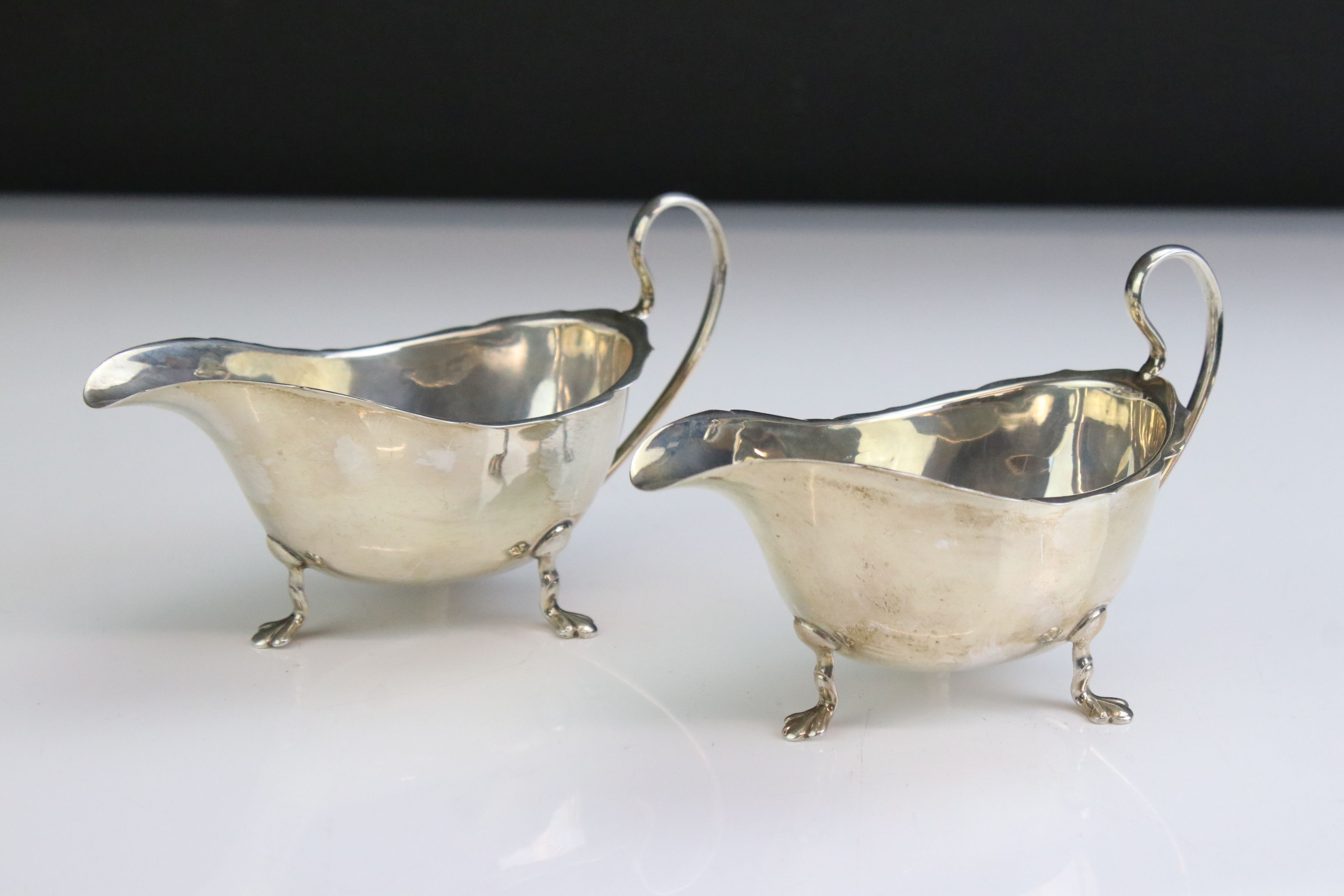 George V near pair of silver cream jugs with pie crust borders, of polished form, with scrolling