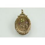 Edwardian oval locket, the front set with peridot, amethyst, garnet and seed pearls to spray design