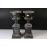 Pair of bronze twin-handled urns mounted on square spelter columns with relief cast scrolling and