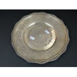 An ornately decorated white metal plate, measures approx 28cm, stamped to verso.
