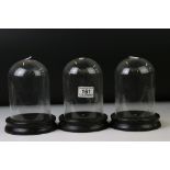 Set of three vintage glass display domes, each approx 18cm in height, on ebonised wooden bases