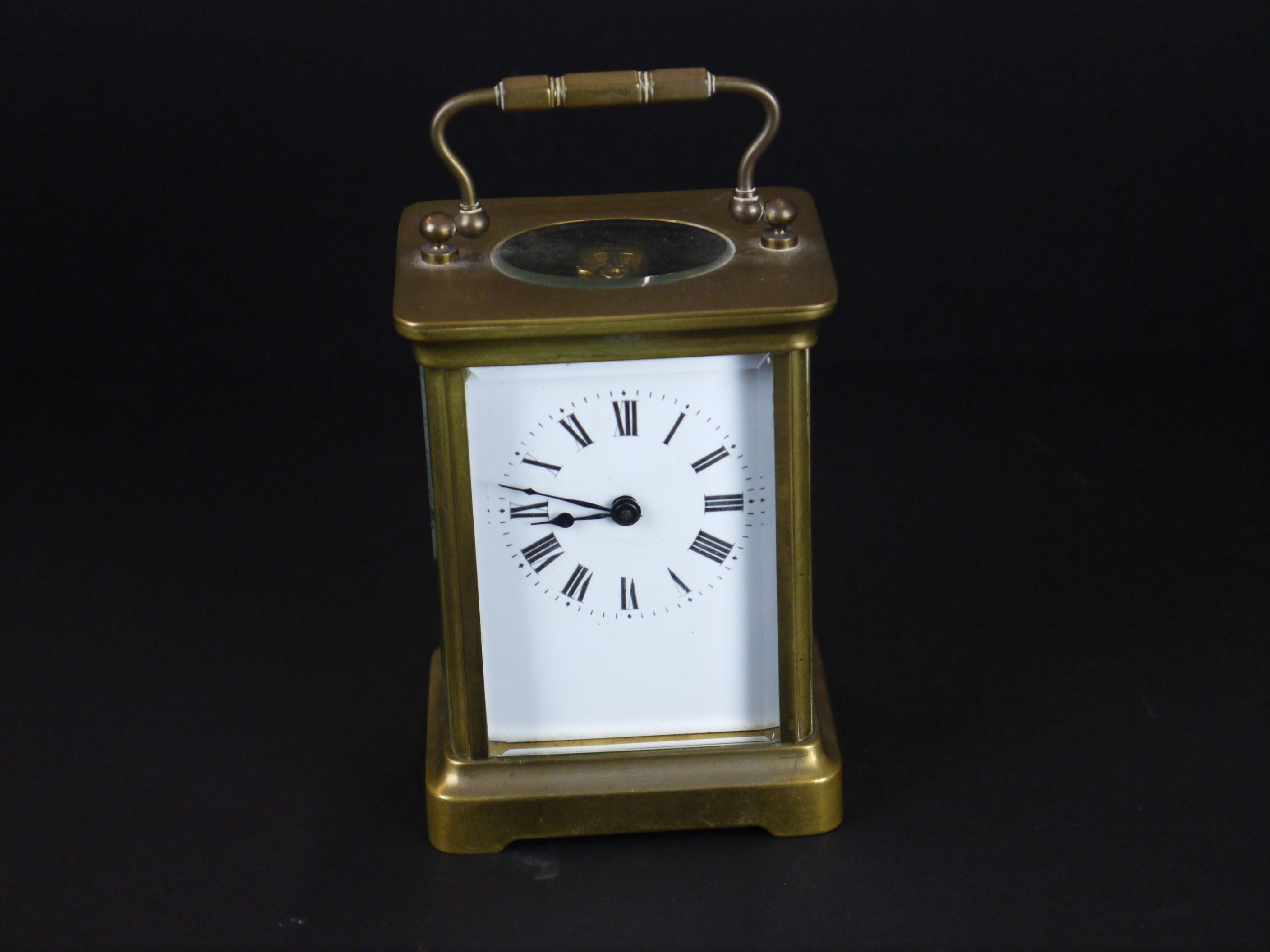 An early 20th century brass cased carriage clock with bevelled glass panels and white enamel dial.