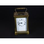 An early 20th century brass cased carriage clock with bevelled glass panels and white enamel dial.