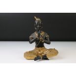 Bronze figure of a seated Thai Buddha, cross-legged playing a pipe, dressed in gilt traditional