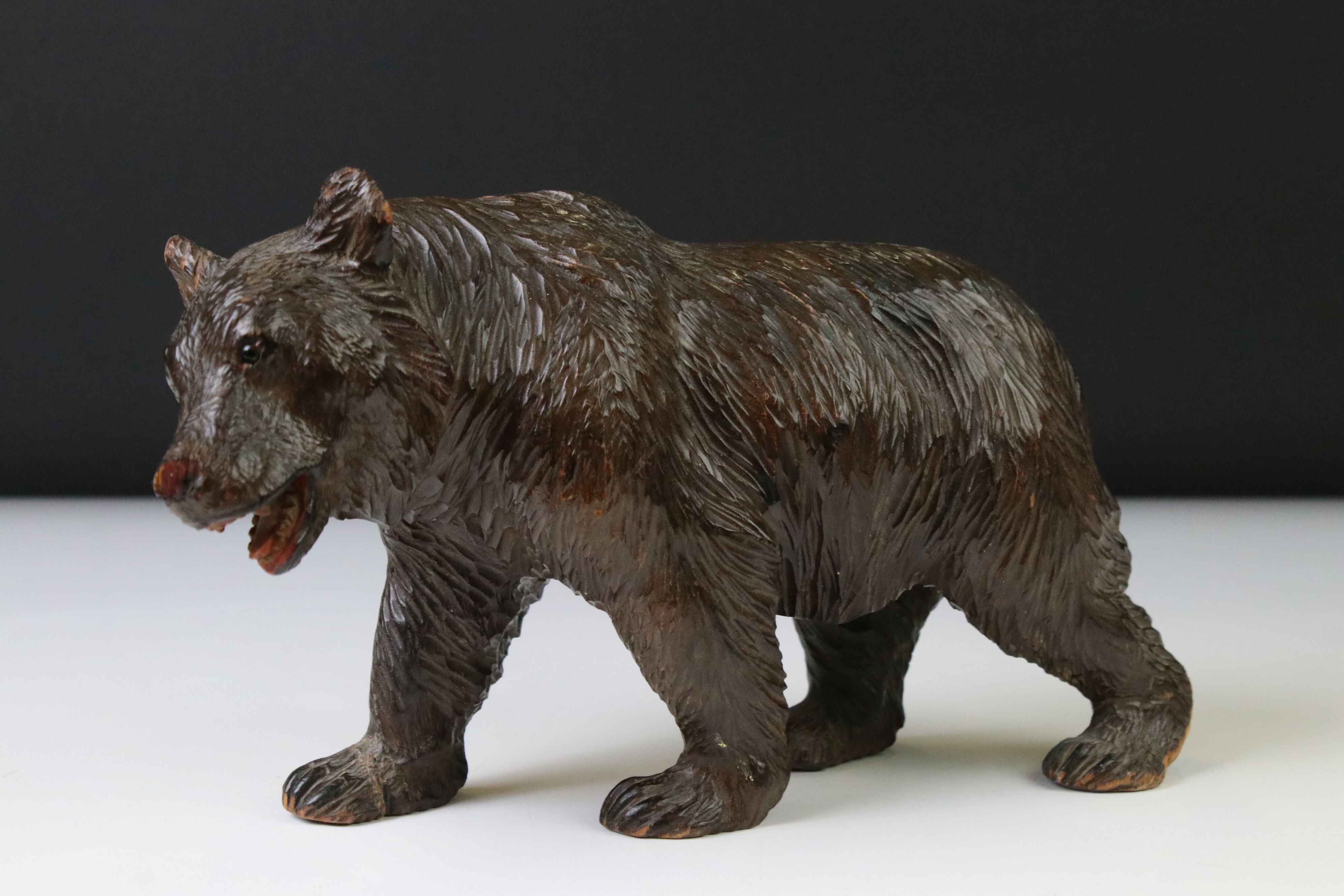 Black Forest style carved figure of a walking bear, mouth open, 25cm long (2 paws a/f)