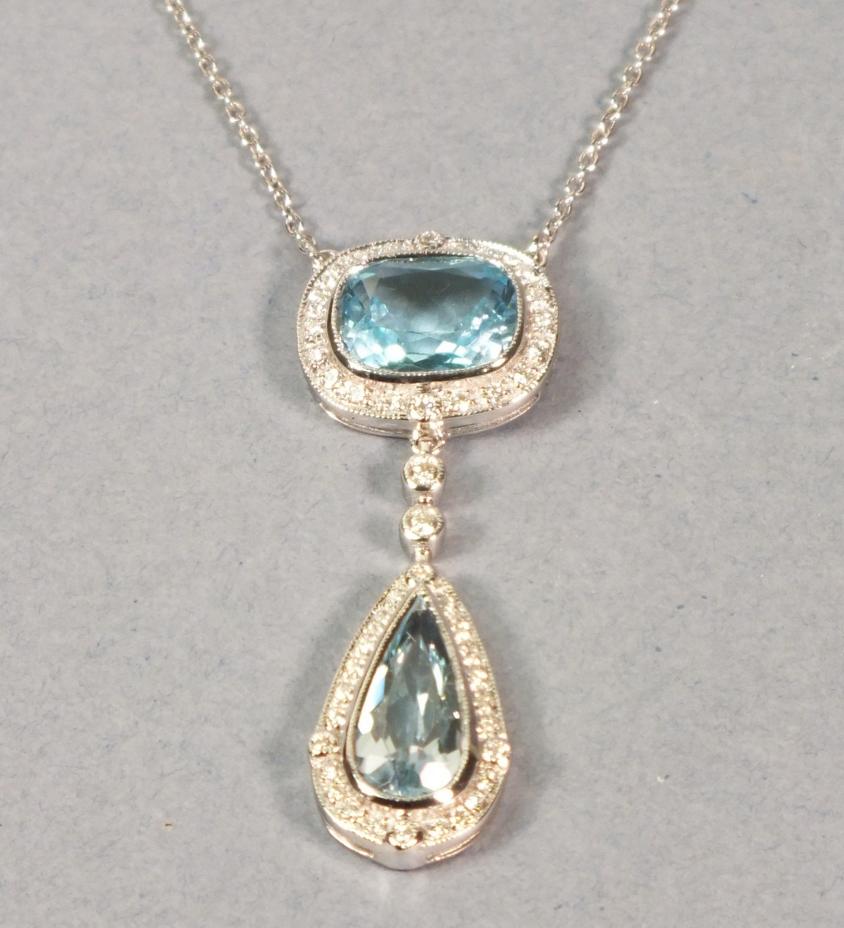 An 18ct white gold topaz and diamond pendant, comprising an emerald cut stone within a diamond