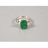 An emerald and diamond dress ring, set in 18ct white gold, the emerald cut central stone flanked