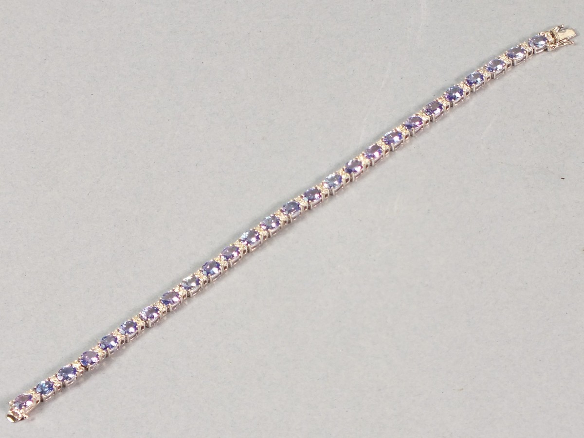 An 18ct white gold tanzanite and diamond line bracelet, the oval cut stones interspersed with