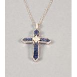 A 18ct white gold sapphire and diamond cross, pave set sapphires within a diamond border and diamond