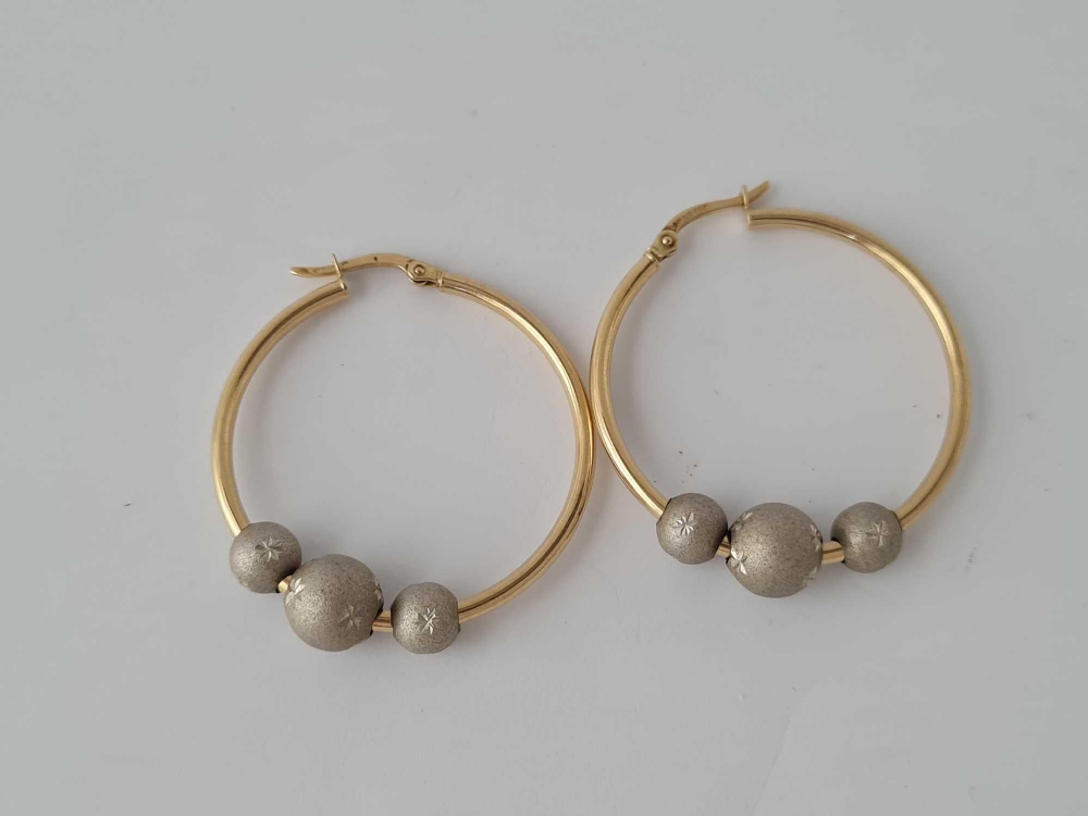 A pair of large hoop earrings with frosted ball decoration 14ct gold - 5.9 gms