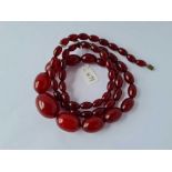 A LONG STRING OF CHERRY AMBER BEADS - 65 GMS