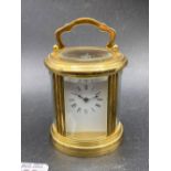 An oval travelling clock with bevelled glass panels, swing handle, 4" high