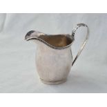 A Chester silver helmet shaped cream jug with leaf capped handle, 3.5” high, 1909 by RH, 57 g.