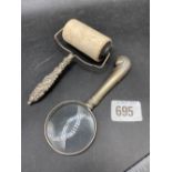 A silver handled stamp roller an a magnifying glass with silver handle