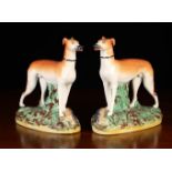 A Pair of Staffordshire Greyhound on grassy bases encrusted with clumps of foliage with game at