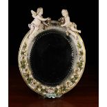 An Ornamental Oval Mirror set in a porcelain frame encrusted with a garland of white roses along