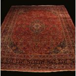A Large Persian Wool Carpet woven with flowers on a claret ground centre field with dark blue