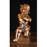A Baroque Carved Walnut Putto depicted with curly hair and draped loin cloth (A/F),