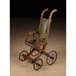 A Late 19th Century Oak Folding Doll's Push Chair with padded seat and back covered in green faux