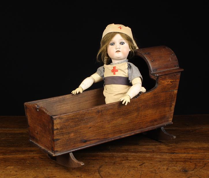 A 19th Century Childs Doll Crib and a German Bisque-headed Doll with brown mohair wig,