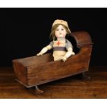 A 19th Century Childs Doll Crib and a German Bisque-headed Doll with brown mohair wig,