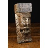 A 16th Century Oak Corbel relief carved with Green Man face mask bearing teeth amidst a surround of