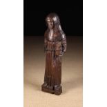 A 13th/14th Century English Oak Carving of a Cowled Monk holding a heavy bound book,