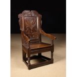 A 17th Century Joined Oak Wainscot Chair. The scrolling cresting rail carved with pendant leaves.