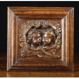 A Small 17th Century Oak Panel carved with a pair of cherub heads nestled within entwined feathery