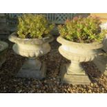 A pair of stone effect garden urns on stands, 45cm high, 45cm diameter