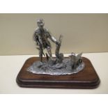 A plated figure of gamekeeper and dog, 23cm wide, in good condition