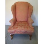 A good quality walnut Queen Anne style wingback armchair on shaped legs united by turned