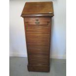 A walnut tambour front cabinet with a rising top, 120cm tall x 50cm x 43cm
