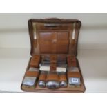 A Drew and sons leather Gentleman's travel case with four silver top bottles, two silver brushes and