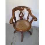 A Victorian oak swivel desk chair with a cane seat having a brass plaque - This oak chair was made