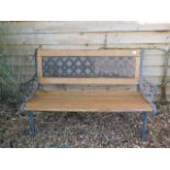 A cast iron wooden slatted garden bench, 127cm wide, in weathered condition