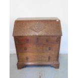 A Robert Mouseman Thompson style adzed oak four drawer bureau with a carved Welsh Dragon on the fall