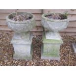 A pair of stone effect urns on stands, 74cm tall x 40cm diameter