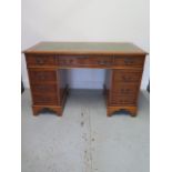 A modern yew effect 8 drawer twin pedestal desk with a leather inset top, 76cm tall x 122cm x 61cm