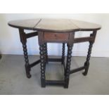 An antique oak dropleaf gateleg table on bobbin turned supports with a long drawer, 67cm tall x 68cm