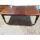A 19th mahogany pullout dining table with one associated leaf on turned inverted tulip carved
