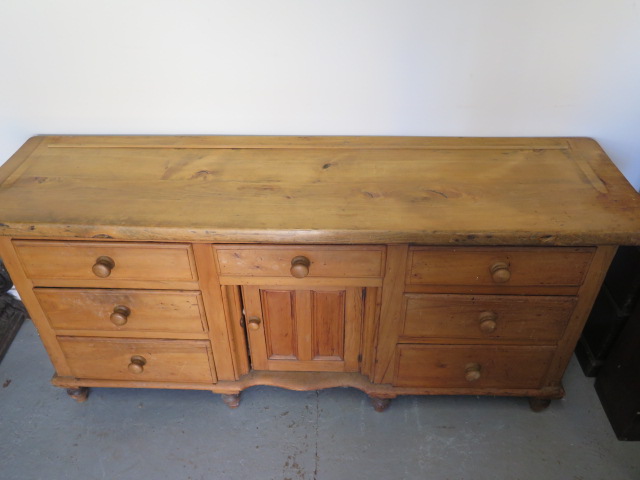 A Victorian stripped pine dresser with 7 drawers and a central door, 82cm tall x 172cm x 46cm - Image 2 of 2