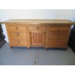 A Victorian stripped pine dresser with 7 drawers and a central door, 82cm tall x 172cm x 46cm