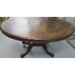A Victorian oval tilt top walnut dining table on a quatrefoil scroll base, 76cm tall x 153cm x 121cm