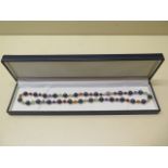 A good quality string of black pearls and semi-precious stones with 18ct white gold clasp and beads,