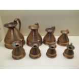 A set of 8 copper measuring jugs ranging from 1/8 Gill to a Quart, 17cm tall