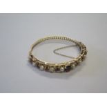 A pretty hallmarked 9ct yellow gold garnet and pearl hinged bangle with safety catch and chain,