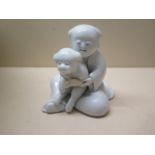 A 19th century Japanese Hirado pottery model of a seated figure holding a dog, 10cm x 9cm, repair to